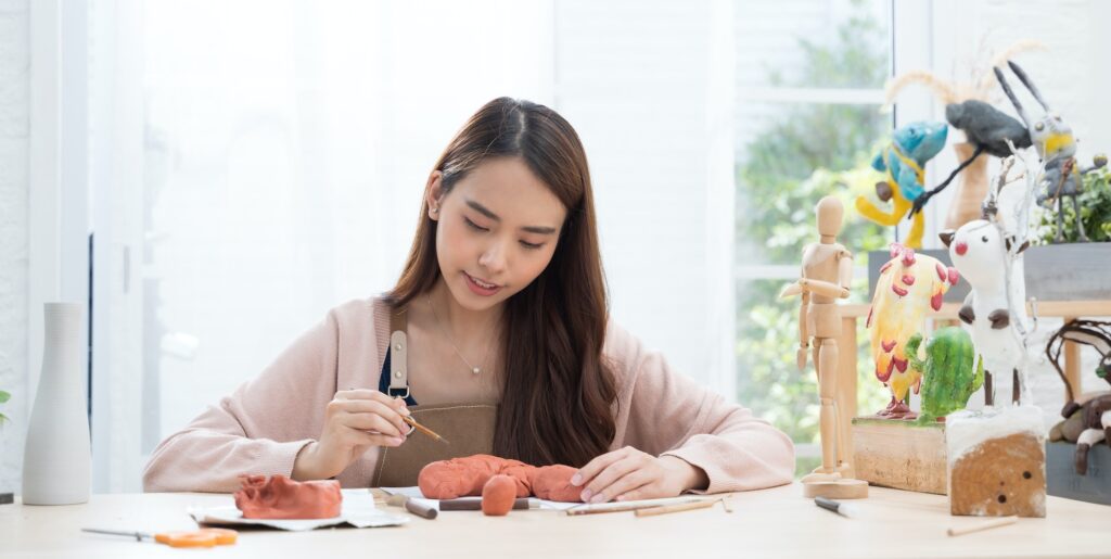 Young Asian girl making a sculpture with modeling clay at home .hobby clay sculpt concept